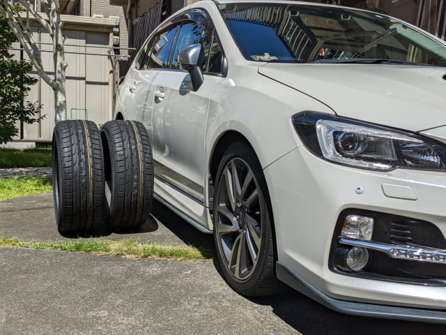 白い車の横に置かれたタイヤ